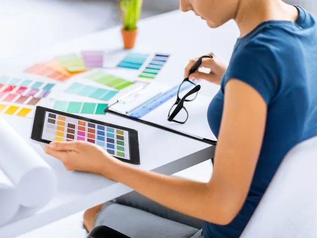 A Graphic Designer is reviewing color swatches both on an iPad, as well as on paper